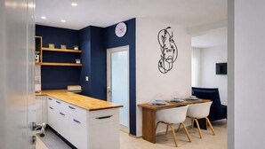 A modern kitchen with white cabinets, a wooden countertop, and a dining area with a table and chairs. - Lovely 1-Bed Apartment in lac1 Tunis (Tunis)