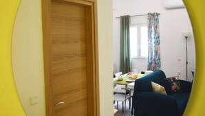 A room with a wooden door, a dining area with a table and chairs, and a dark blue sofa. - Pirgos Colorful Studio, Sleeps 2, Parking WiFi Ac (Pirgos Monofatsiou Heraklion)