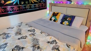 A bedroom with a bed, a colorful tapestry, a skull mural, and string lights. - Lovely 1-Bed Apartment (Istanbul)