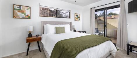 A bedroom with a bed, a nightstand, a ceiling fan, and artwork on the walls.
