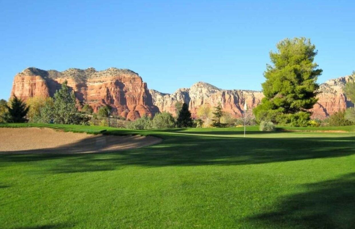 A golf course with a clear view of red rock formations in the background.