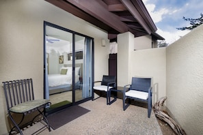 A balcony with a bed, two chairs, and a bench.