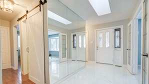 A spacious hallway with a sliding door, white tiled flooring, and a skylight. - Wasaga Beach cottage  (Wasaga Beach)