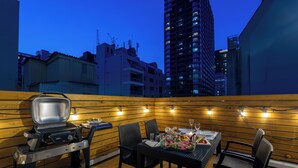 An outdoor dining area with a grill, chairs, and a table set for a meal. - ONE WORLD Sakaisuji Hommachi (Osaka)