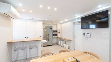 A modern kitchen with stainless steel appliances, a wooden dining table, and clear plastic chairs.