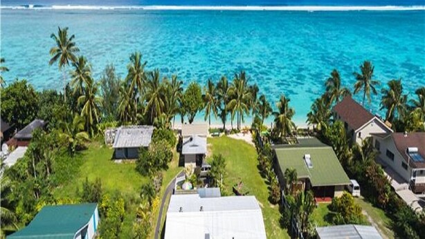 A coastal residential area with houses, palm trees, and a view of the ocean. - Ann's Beach House (Rarotonga)