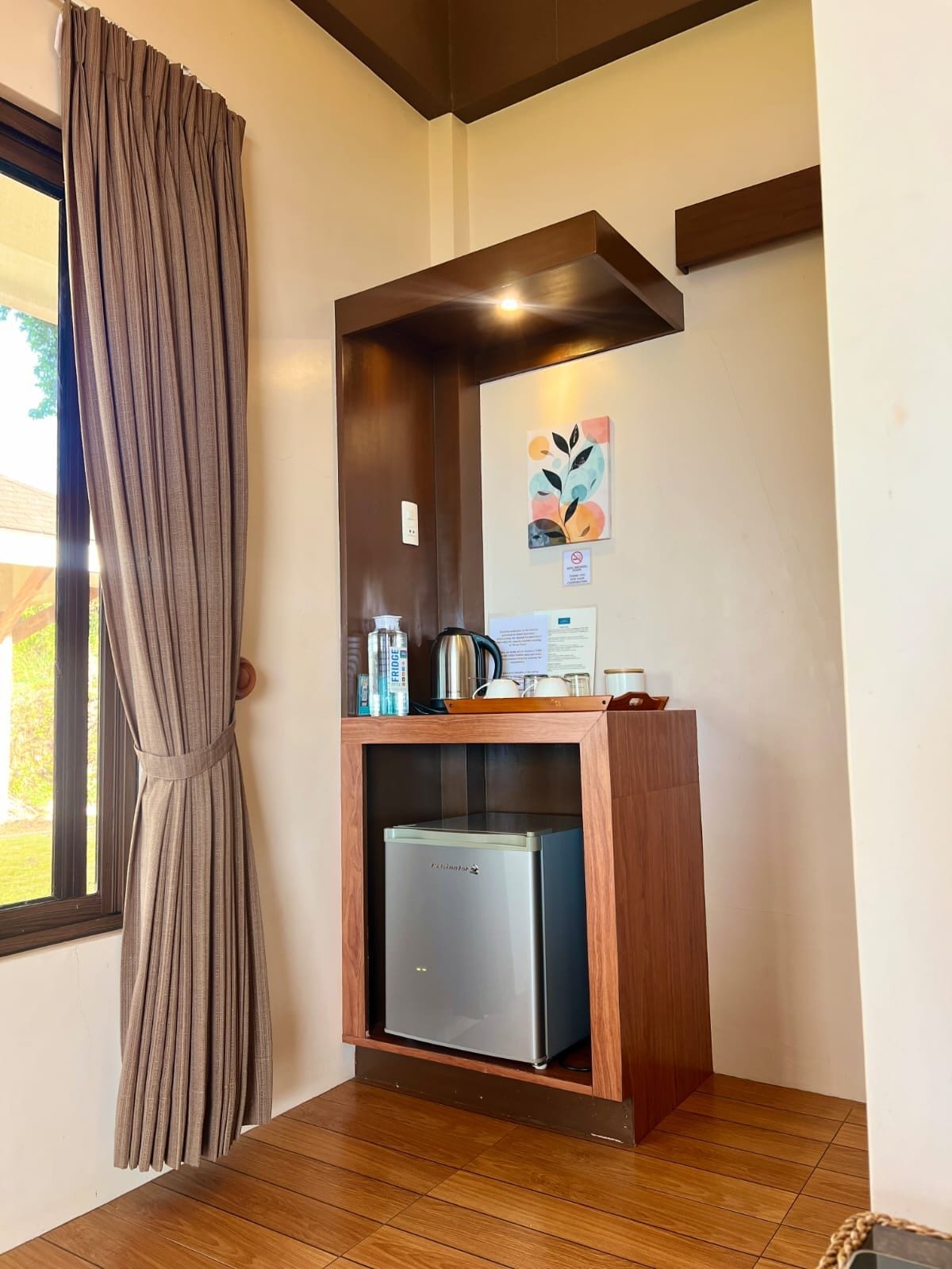 Una kitchenette compacta con un refrigerador empotrado, una cafetera y un hervidor sobre la encimera.