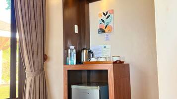 Una kitchenette compacta con un refrigerador empotrado, una cafetera y un hervidor sobre la encimera.