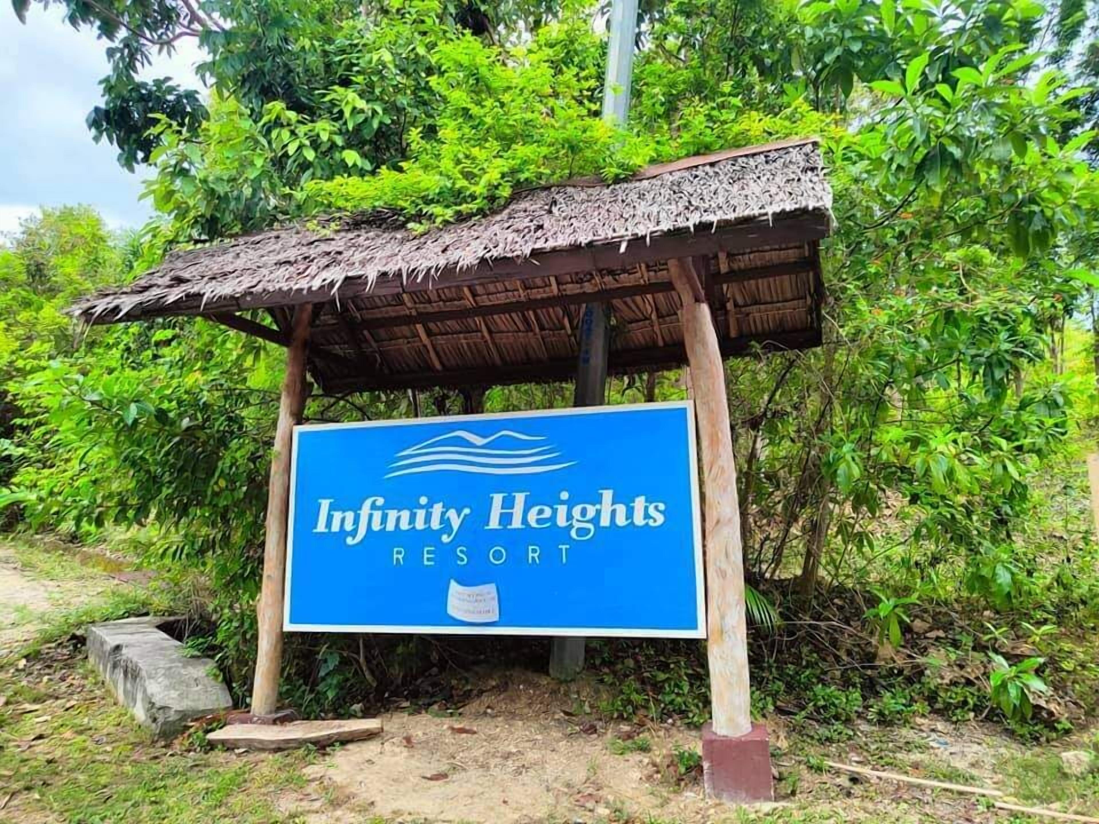 A sign for Infinity Heights Resort with a thatched roof structure.