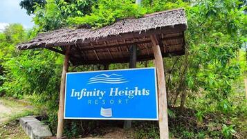 A sign for Infinity Heights Resort with a thatched roof structure.