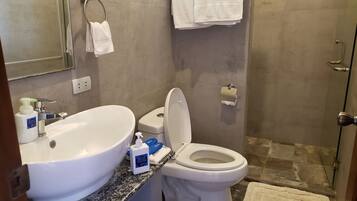 A bathroom with a sink, toilet, and shower. There are toiletries on the counter.