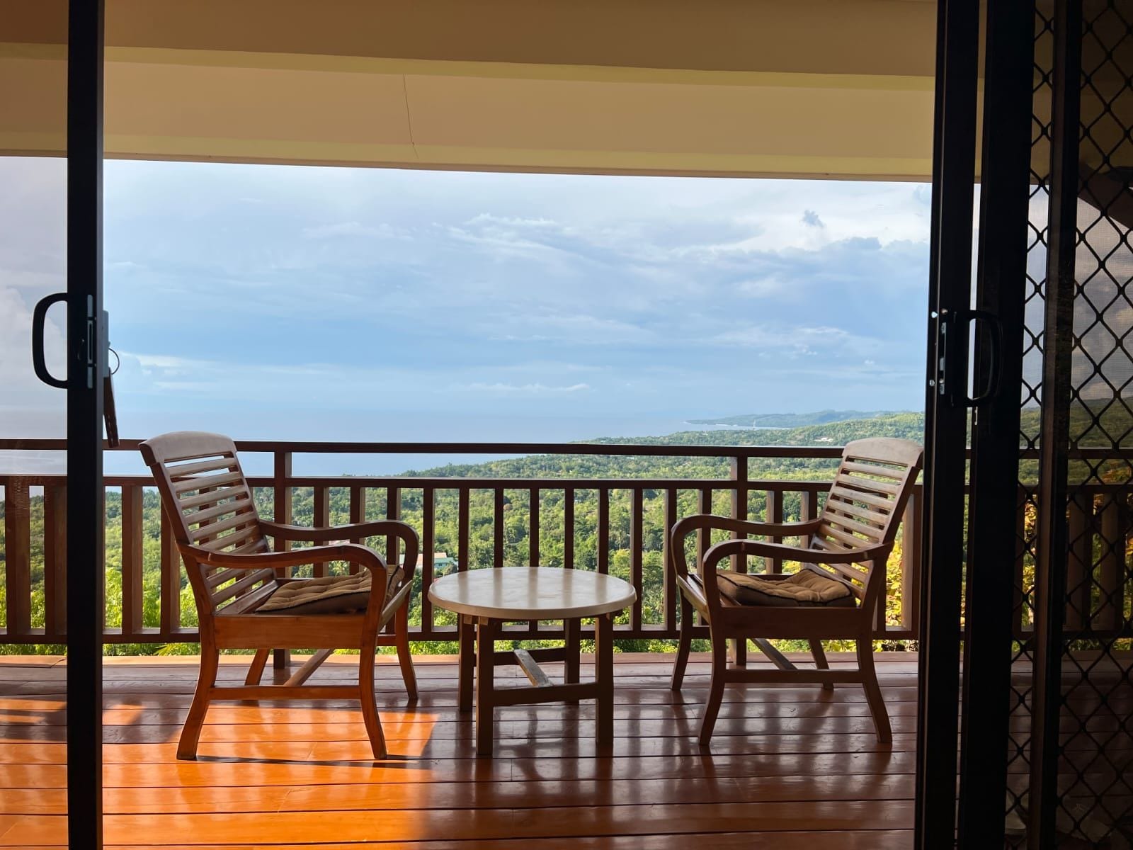 Un balcon avec deux chaises en bois et une petite table, offrant une vue sur un paysage pittoresque.