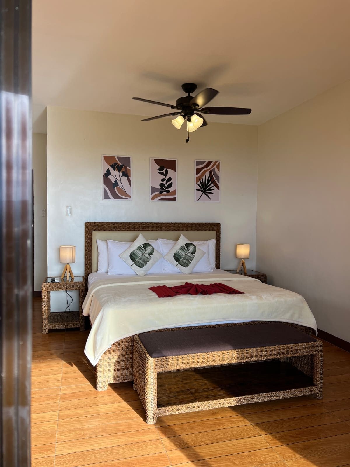 Une chambre à coucher avec un lit, un ventilateur de plafond, des lampes de chevet et des œuvres d’art murales.