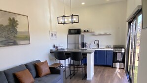 A modern kitchen with a central island, bar stools, and a dining table.