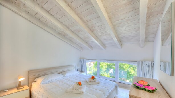 A bedroom with a bed, bedside table, window, and a wooden dresser. - Golden Terrace Leggiuno 2BR/2BA Walk to the Lake, Leggiuno, Italy (Leggiuno)