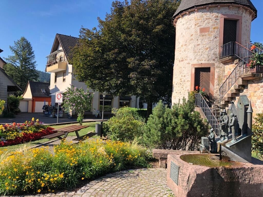 Ein Innenhof mit einem Steinturm, einer Bank und einer Statue.