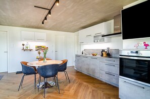 Une cuisine moderne avec un coin repas, un plancher en bois et un four encastré.