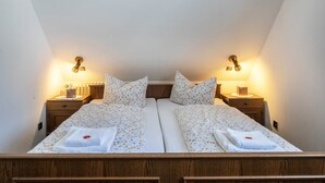 Una cama doble con ropa de cama floral, dos mesitas de noche con lámparas y un cabecero de madera.