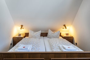 A double bed with floral bedding, two bedside tables with lamps, and a wooden headboard.