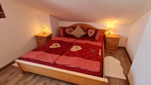 A bed with a red and white checkered bedspread, two heart-shaped pillows, and two bedside lamps. - Apartment 'Haus Bergblick' with Balcony and Wi-Fi (Mittenwald)