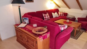 A cozy living room with a red sofa set, a wooden side table, and a lamp. - Apartment 'Haus Bergblick' with Balcony and Wi-Fi (Mittenwald)