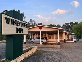 Un Wind Tree Inn con área de estacionamiento techada y un edificio de un piso.