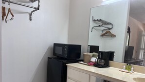 A compact bathroom with a sink, mirror, and a small refrigerator.
