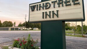 A sign for Windtree Inn with a clear view of the surrounding area including a road and some greenery.