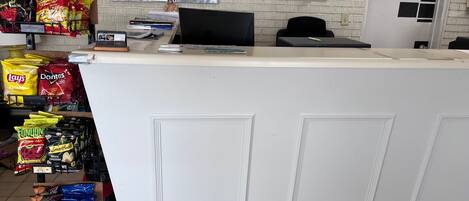 A counter with snacks, a computer, and a wall with various notices.