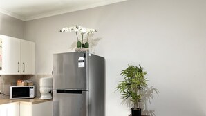 Una cocina con un refrigerador de acero inoxidable, un microondas y una planta en maceta.