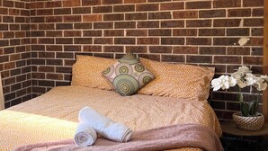 Una cama bien hecha con un edredón estampado, almohadas y una toalla enrollada.