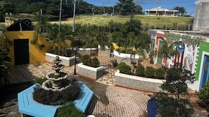 A courtyard with a fountain, potted plants, and a building with a mural.