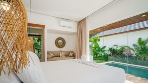 Una habitació d'hotel moderna amb un llit gran, un mirall rodó i vista a una piscina.