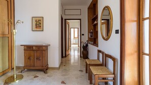 Un couloir avec une armoire en bois, un miroir et une chaise.