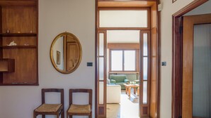Un couloir meublé de meubles en bois, avec un miroir et une vue sur un salon comprenant un canapé et une table.