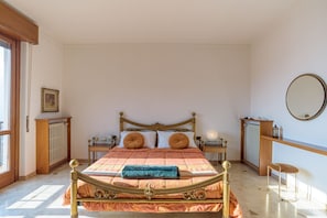 A bedroom with a bed, bedside tables, a mirror, a radiator, and a window. - GuestHost - Bright villa with lake view, can accommodate up to 6 people.The property is located in a residential area of Mandello del Lario, a town on the shores of the Lecco branch of Lake Como.The area is ideal for both relaxing stays and trekking love (Mandello del Lario)