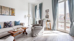 Een woonkamer met een bank, fauteuil, salontafel en kunstwerk aan de muur.
