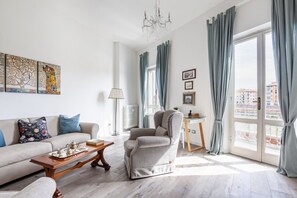 A living room with a sofa, armchair, coffee table, and artwork on the wall.
