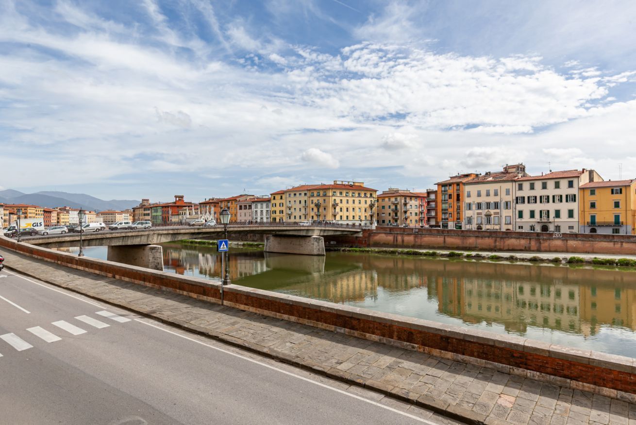 Un riu amb edificis al costat i un pont al mig.