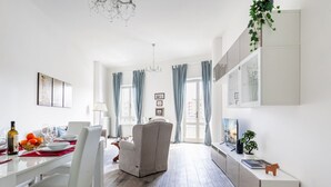 Een moderne eetruimte met een witte tafel, stoelen en een kroonluchter.