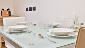 Une table à manger dressée avec des assiettes blanches, des bols et des verres transparents, ainsi qu’une cuillère et un salier posés sur la table.