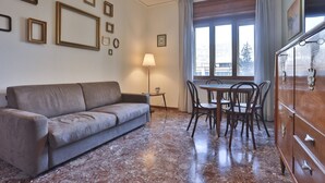 Une pièce comprenant un canapé, une table à manger, des chaises, une lampe et un meuble.