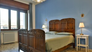 Une chambre à coucher avec un lit en bois, deux lampes de chevet, un radiateur et une fenêtre avec des rideaux.