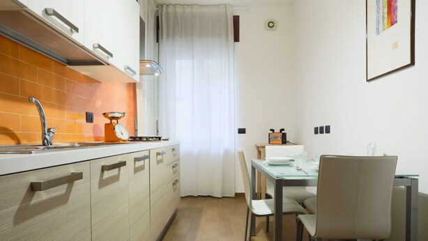 Une cuisine compacte comprenant un évier, une cuisinière et un coin repas avec des chaises et une table.