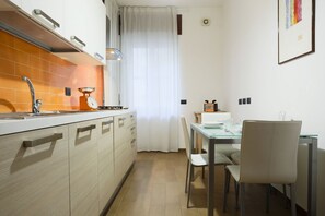 A compact kitchen with a sink, stove, and dining area with chairs and a table. - GuestHost - Spacious apartment that can accommodate up to 4 people, featuring a double bedroom, two bathrooms and two balconies. The accommodation is located in the Torrione district, an area in the immediate vicinity of the center and the seafront, and  (Salerno)