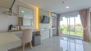 A modern hotel room with a large window, a flat-screen TV, a desk with a chair, and a small trash bin. - Sananwan Hometel (Bang Phli)
