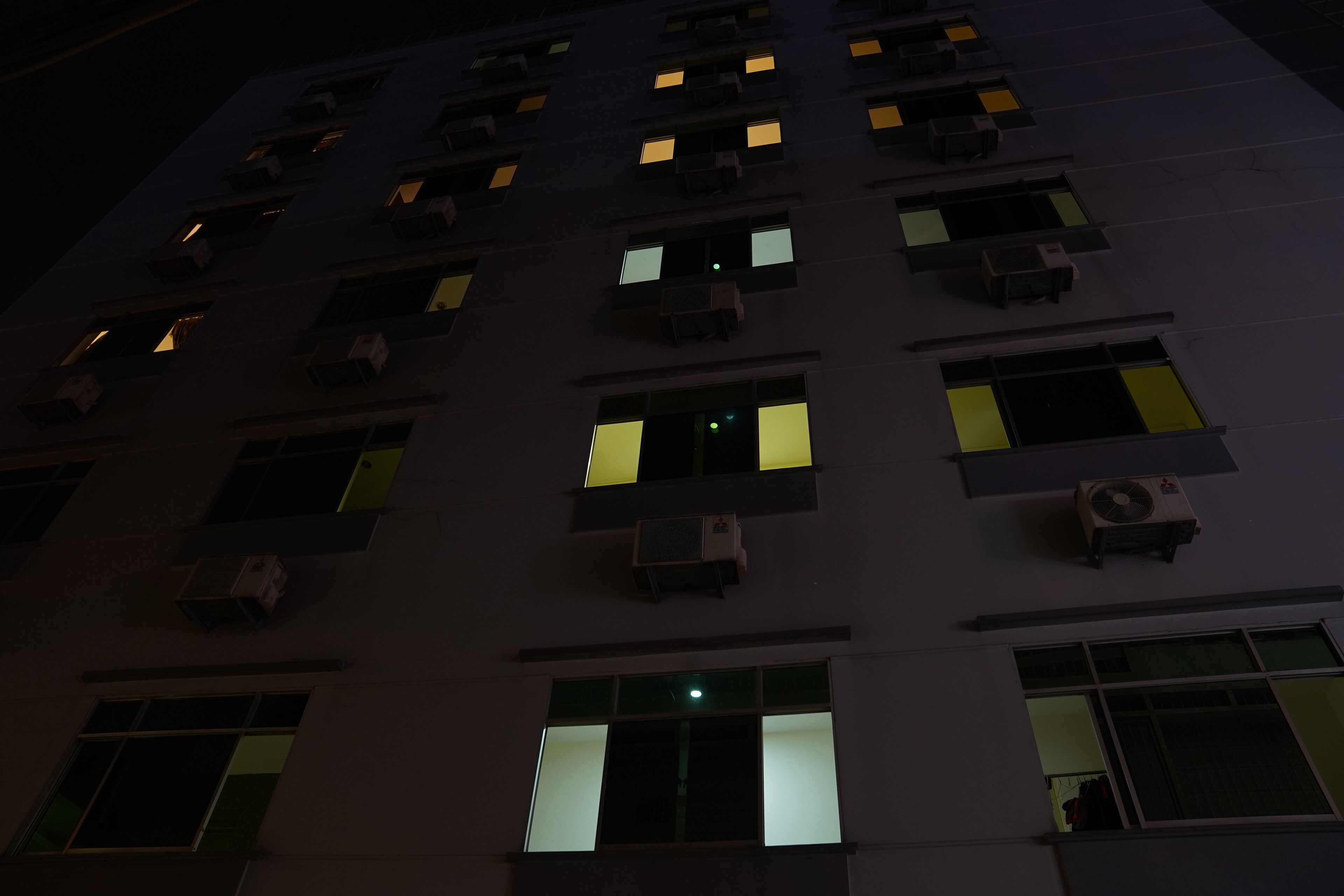 A multi-story building with numerous windows, some illuminated.