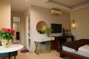 Une chambre d’hôtel avec un lit, un bureau doté d’un miroir, une télévision et une plante en pot.