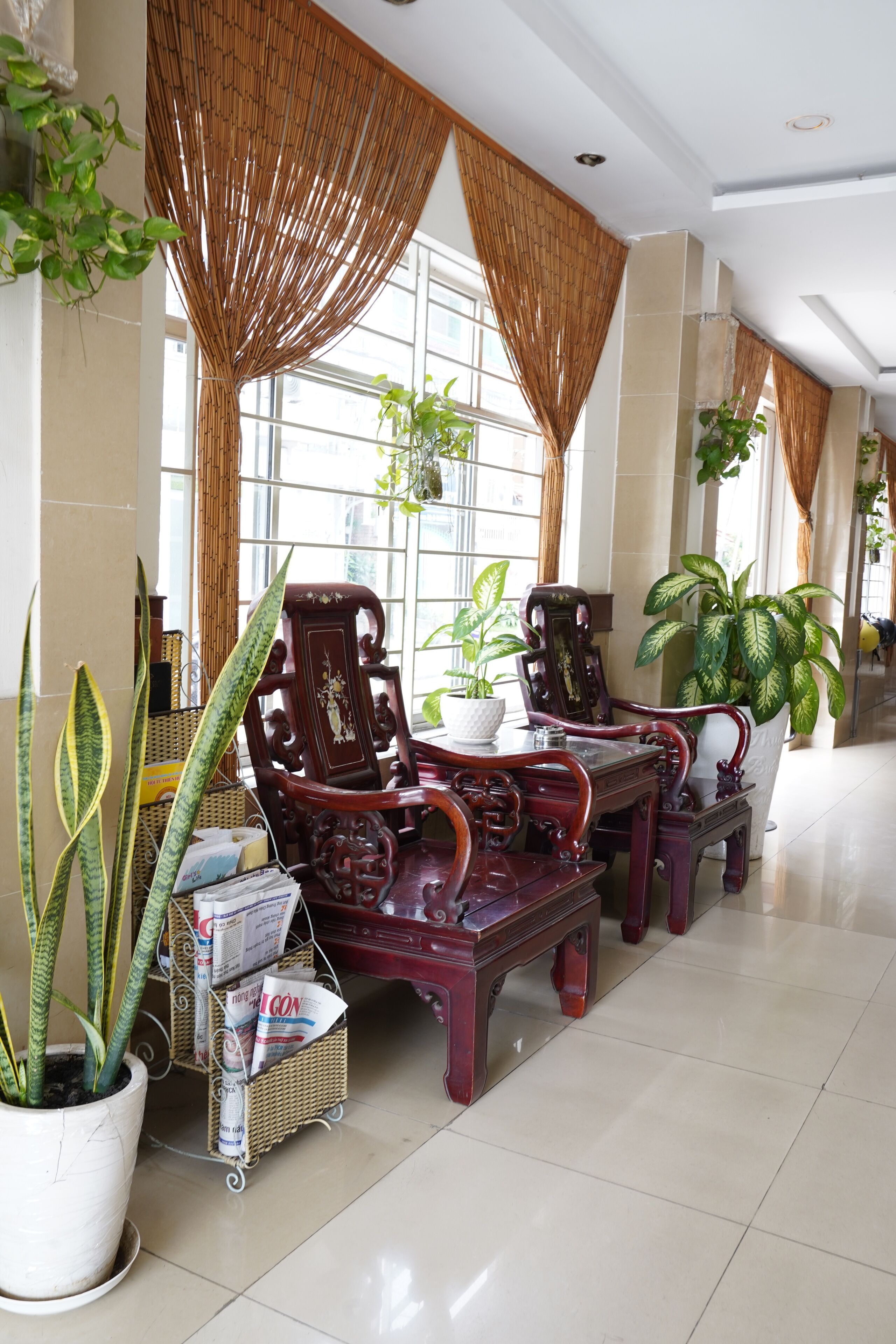 Un hall amplio con muebles de madera tradicionales, ventanas grandes y plantas en macetas.