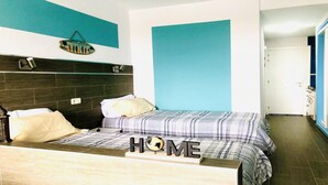 A bedroom with a bed, a bedside table, and a wall-mounted shelf.